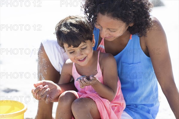 Mixed race mother and daughter playing on beach