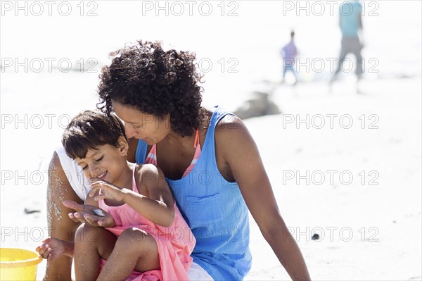 Mixed race mother and daughter playing on beach