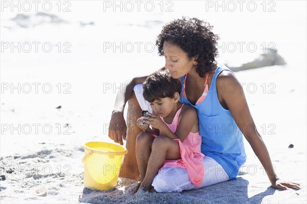 Mixed race mother and daughter playing on beach