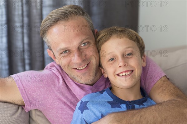 Caucasian father and son hugging on sofa