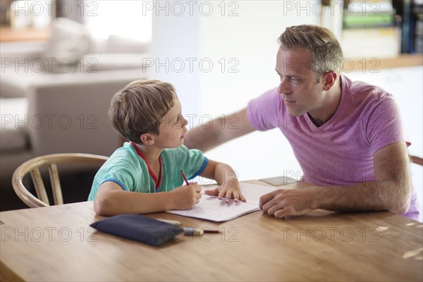 Caucasian father and son drawing at table