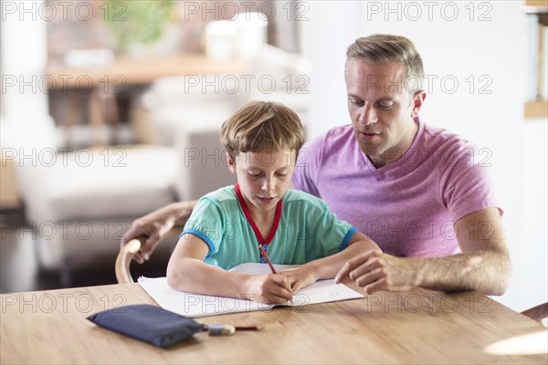 Caucasian father and son drawing at table