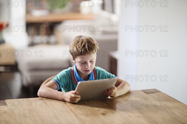 Caucasian boy using digital tablet at table