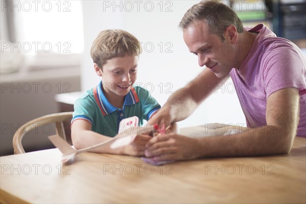 Caucasian father and son examining model airplane at table