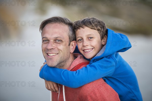 Caucasian father carrying son piggyback outdoors