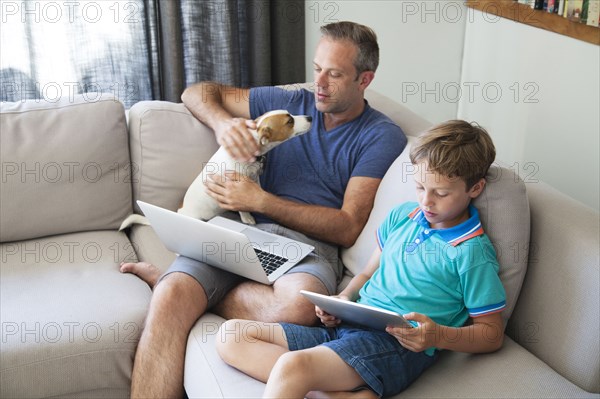 Caucasian father and son using technology on sofa