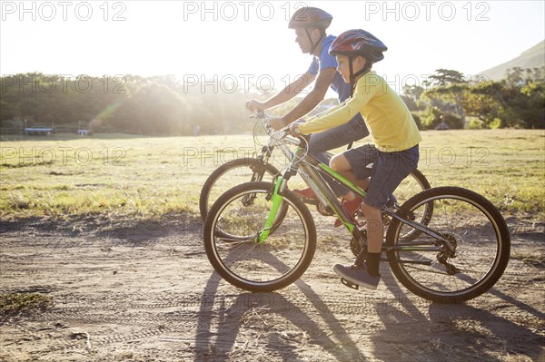 Caucasian father and son riding bicycles on dirt path