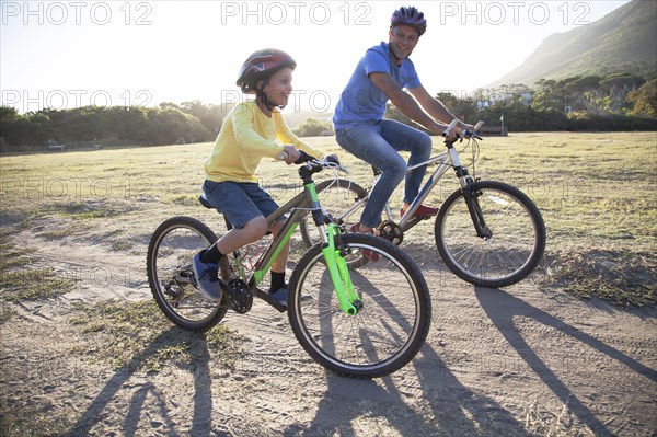 Caucasian father and son riding bicycles on dirt path
