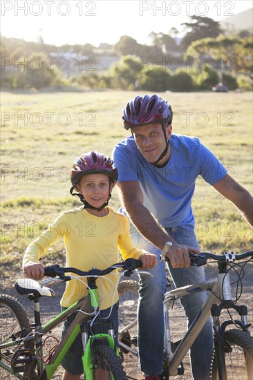 Caucasian father and son riding bicycles on dirt path