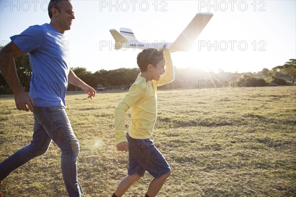 Caucasian father and son flying model airplane in field