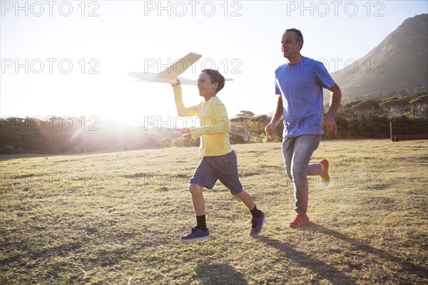 Caucasian father and son flying model airplane in field