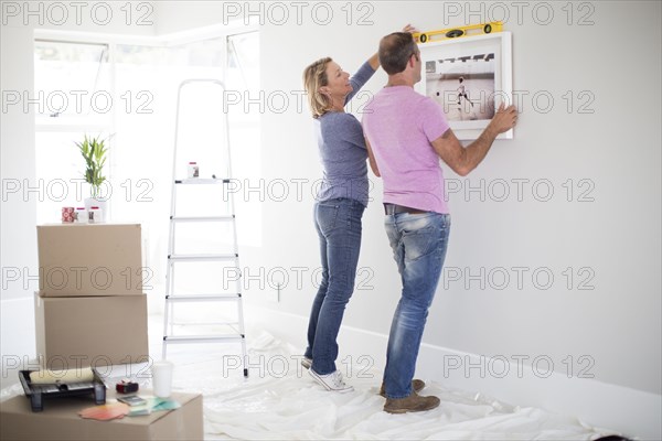 Caucasian couple using level in new home
