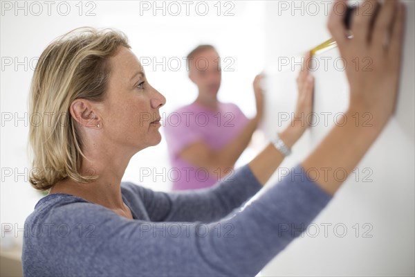 Couple measuring wall in new home