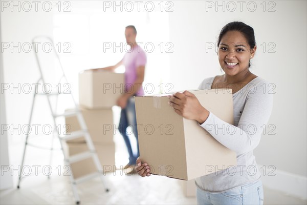 Couple holding cardboard boxes in new home