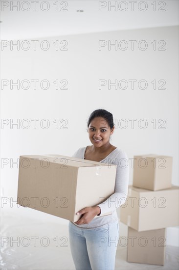 Mixed race woman carrying cardboard box in new home