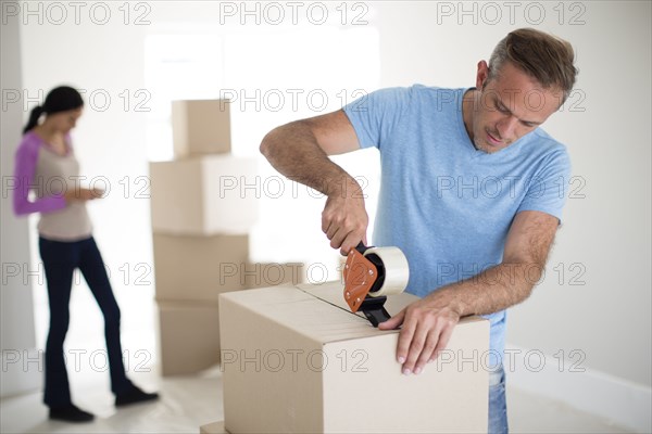 Man taping cardboard box to move