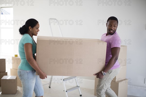 Couple carrying cardboard box in new home