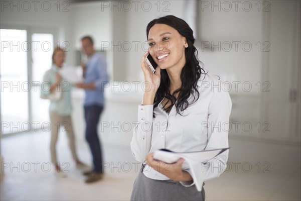 Realtor talking on cell phone with couple in new home