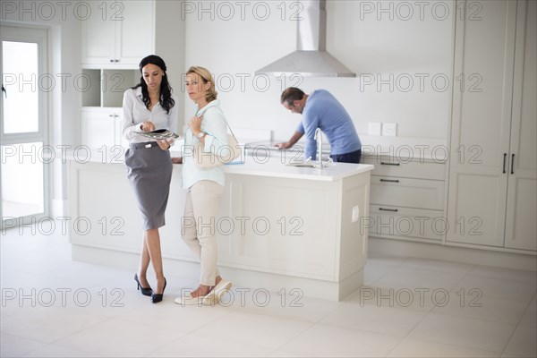 Realtor showing couple kitchen in new home