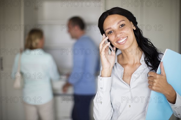 Realtor talking on cell phone with couple in new home
