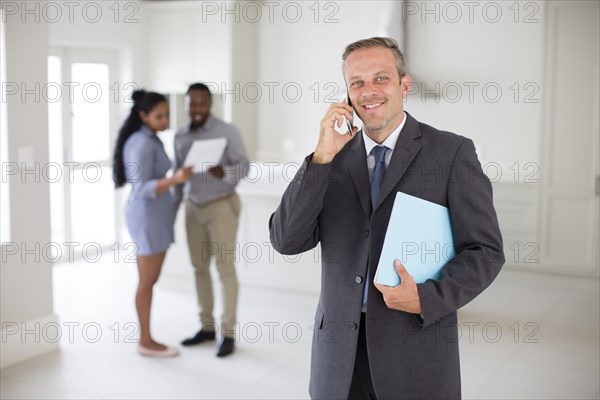 Realtor talking on cell phone with couple in new home