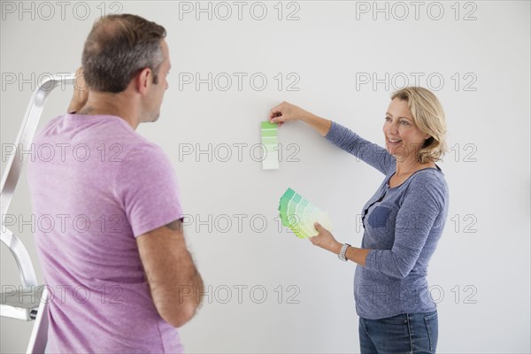Caucasian couple examining color swatches in new home