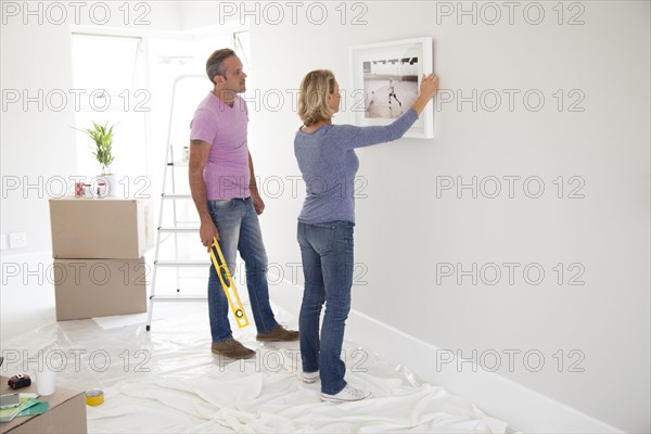 Caucasian couple hanging picture in new home