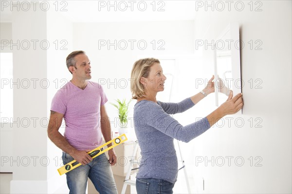 Caucasian couple hanging picture in new home