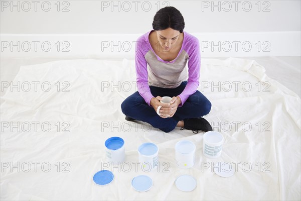 Mixed race woman examining paint samples in new home