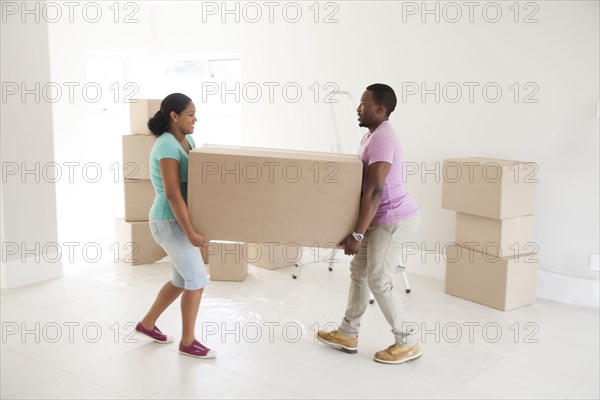 Couple carrying cardboard box in new home