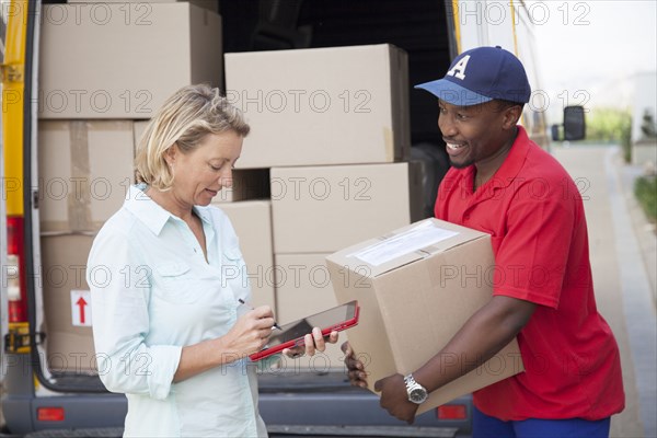 Delivery man holding cardboard box with customer