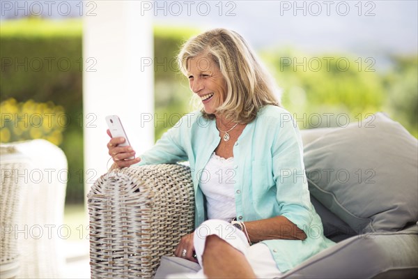 Caucasian woman using cell phone on sofa outdoors