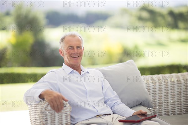 Caucasian man using digital tablet on sofa outdoors