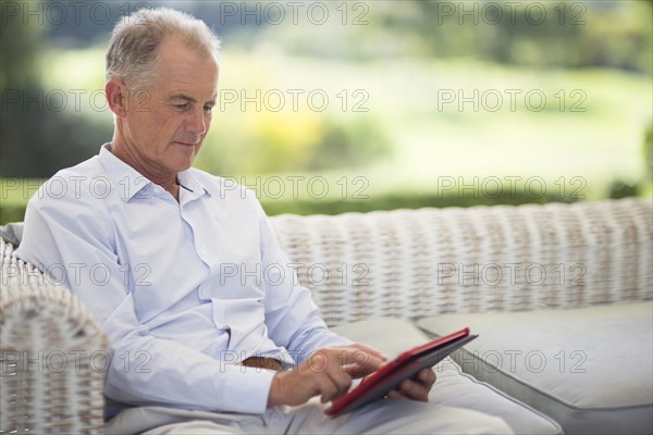 Caucasian man using digital tablet on sofa outdoors