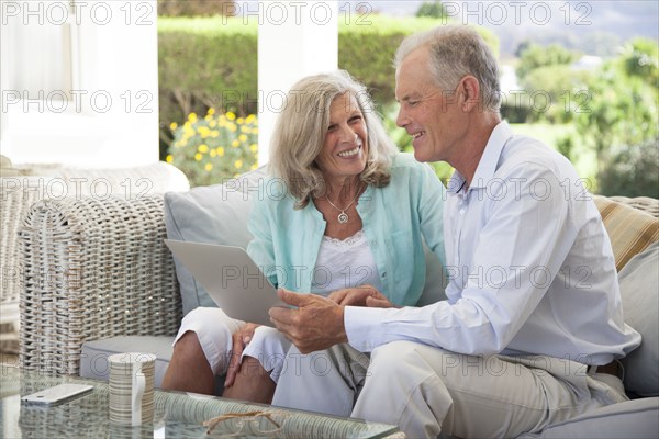 Caucasian couple using laptop on sofa outdoors