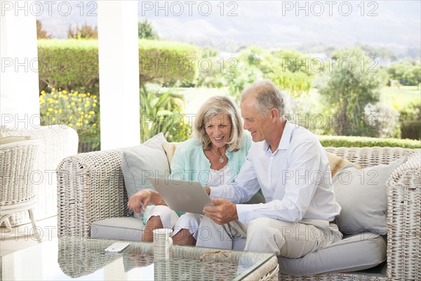 Caucasian couple using digital tablet on sofa outdoors
