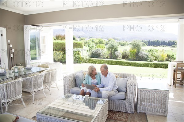 Caucasian couple using digital tablet on sofa