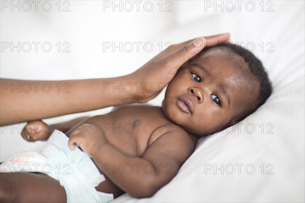 Close up of Black mother patting baby on bed