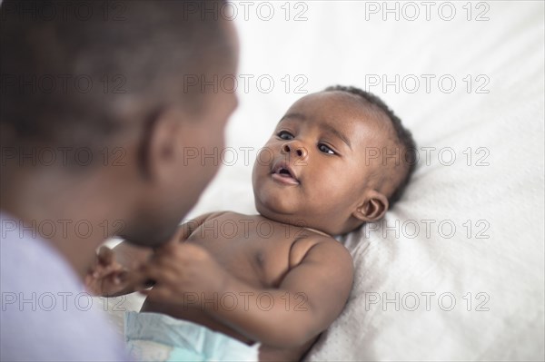 Close up of Black father playing with baby on bed