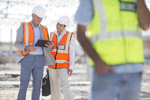 Architects using digital tablet at construction site