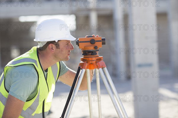 Caucasian surveyor examining construction site