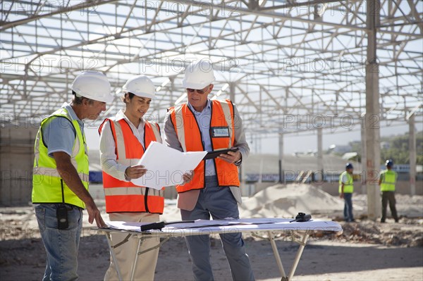 Architects reading blueprints at construction site