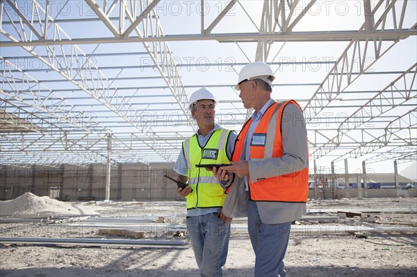 Caucasian architects talking at construction site