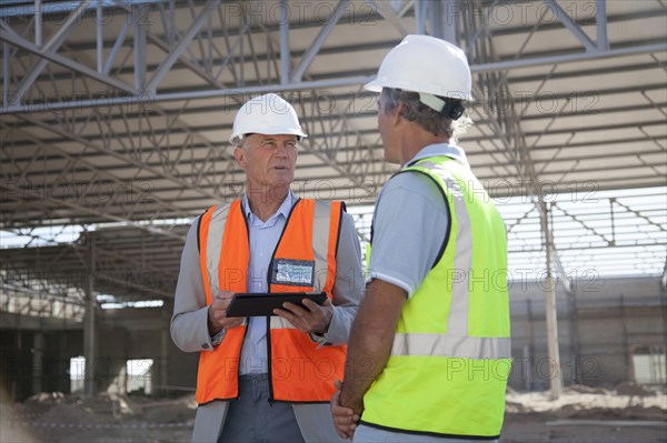 Caucasian architects talking at construction site