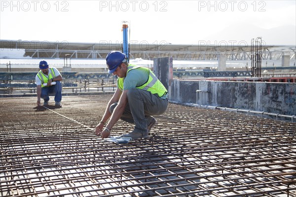 Construction workers arranging rebar at construction site