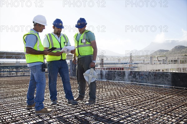 Construction workers talking on rebar at construction site