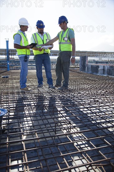 Construction workers talking on rebar at construction site