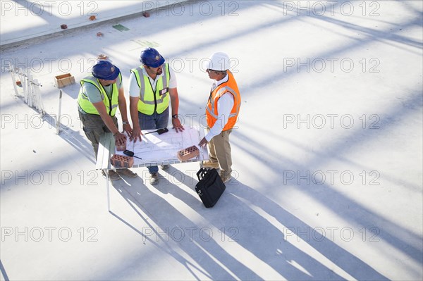 Architects reading blueprints at construction site