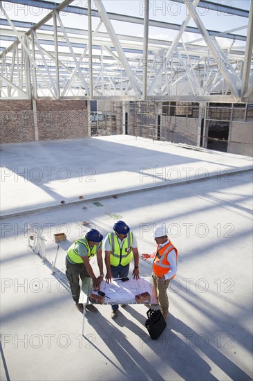 Architects reading blueprints at construction site