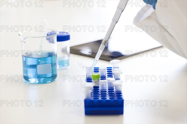 Mixed race scientist pipetting liquid into test tubes in laboratory